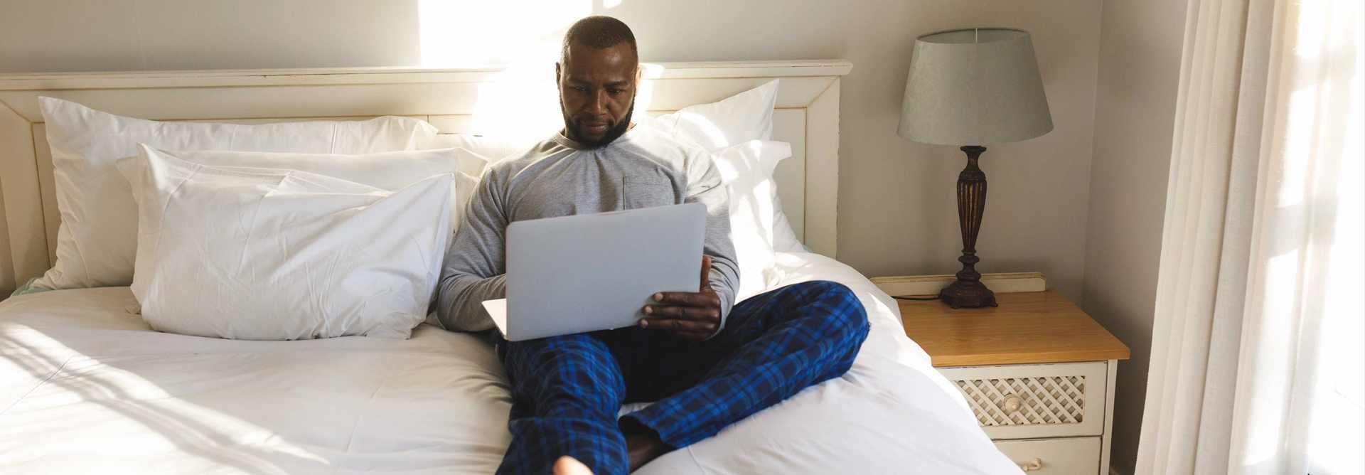 man using laptop and lying on bed